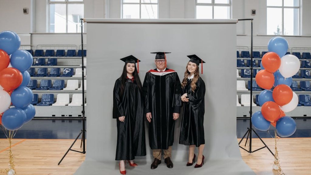 Group graduation portrait with caps and gowns in gymnasium setting.